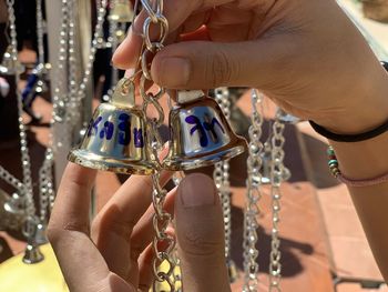 Cropped hand holding bells during sunny day