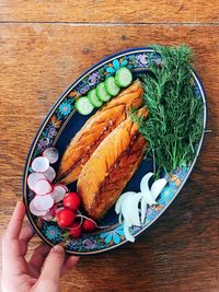 High angle view of person holding bread in plate on table