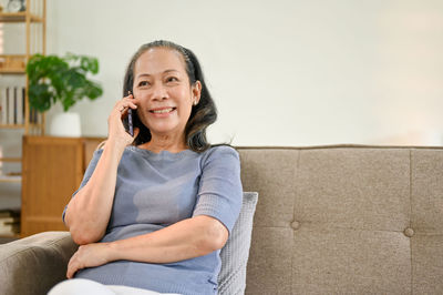 Portrait of young woman sitting on sofa at home