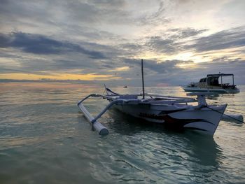 Boat moored on sea against sky during sunset