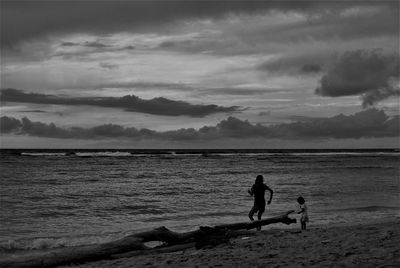 Silhouette people on beach against sky