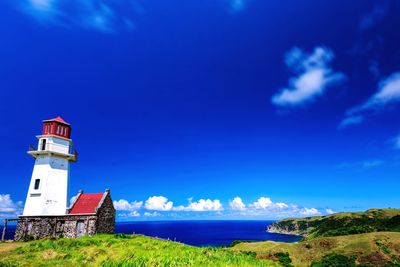 Lighthouse by sea against blue sky