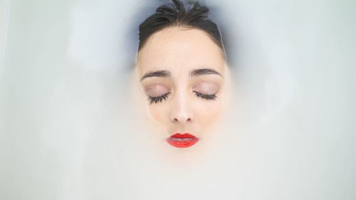 Close-up portrait of young woman against white background