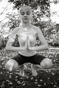 Beautiful young woman practicing yoga at park