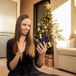 Young woman using mobile phone at home