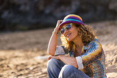Woman wearing sunglasses while sitting at beach