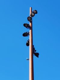 Low angle view of lighting equipment against clear blue sky