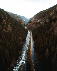 Road by river amidst mountains against sky