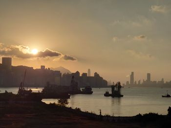 Scenic view of sea and silhouette buildings against sky during sunset