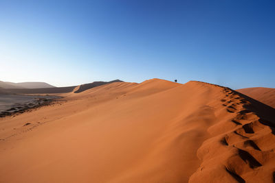 Sand dunes in desert against clear blue sky