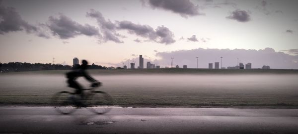 Woman walking on city street against sky