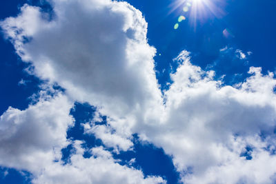 Low angle view of sunlight streaming through clouds