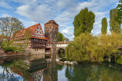 Arch bridge over river by building against sky