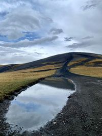 Black road on top of a mountain, with the reflection of a puddle