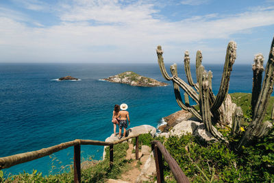 Rear view of couple standing by sea on rock 