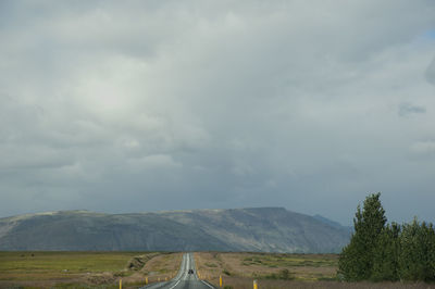 View of country road against cloudy sky