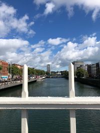 Bridge over river amidst buildings in city against sky