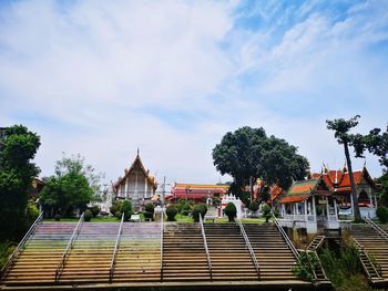 People at temple by building against sky