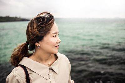 Close-up of woman looking away against sea