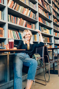 Portrait of smiling young woman sitting on book