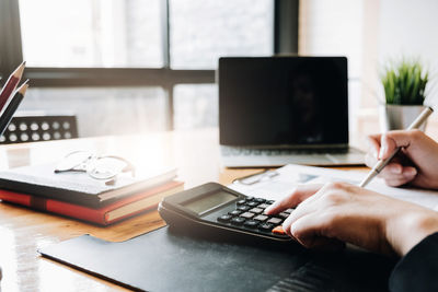 Cropped hands using calculator on table