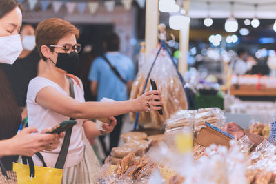 Woman customer in protective mask hand showing online payment in cell phone during covid-19.