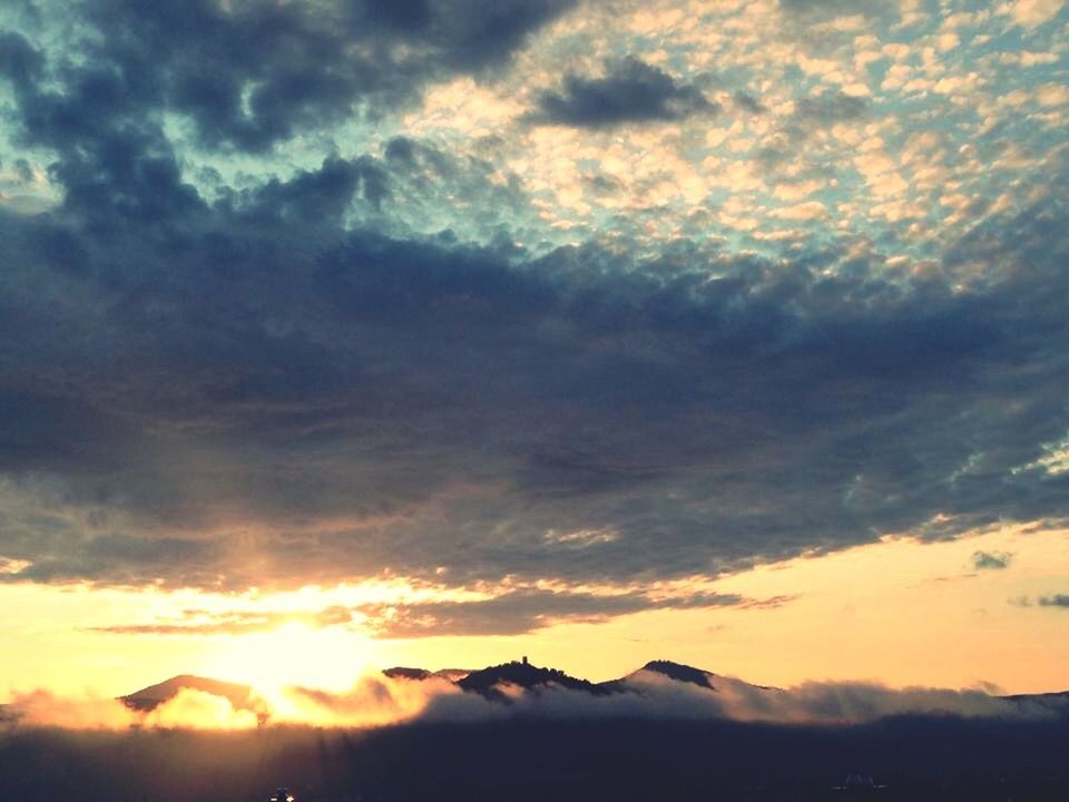 sunset, scenics, sky, tranquil scene, beauty in nature, tranquility, cloud - sky, mountain, silhouette, sun, nature, idyllic, cloud, orange color, cloudy, dramatic sky, majestic, mountain range, landscape, weather