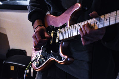 Midsection of man playing guitar