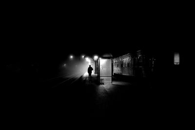 Silhouette man walking in illuminated city at night