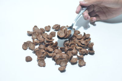 Close-up of hand holding bread over white background