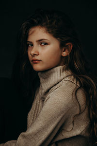 Close-up of young woman against black background