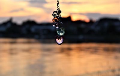 Close-up of water drop on rock against sky during sunset