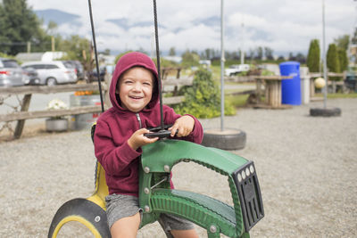 Boy sits on play ride on tractor at farm made from recycled tires