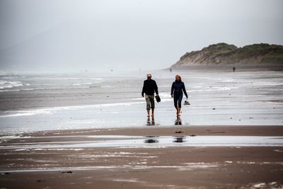 Rear view of people walking on beach