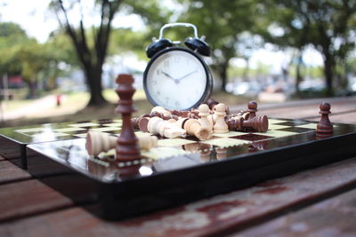 Close-up of clock with chess board on table