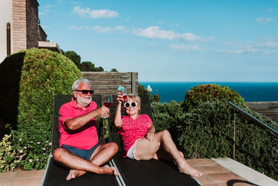 People sitting on beach by sea against sky