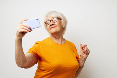 Senior woman taking selfie against white background