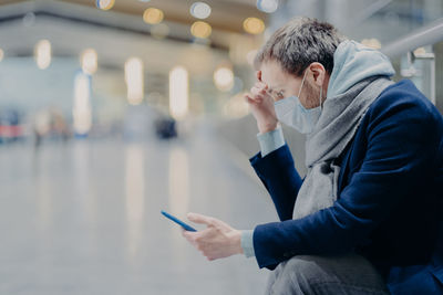 Side view of young man using mobile phone