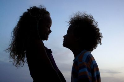 Low angle view of happy siblings against sky