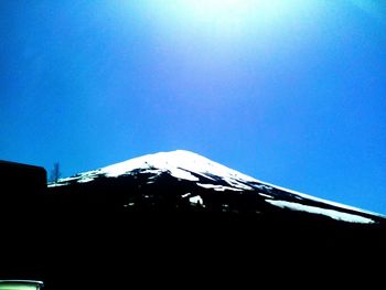 Low angle view of snowcapped mountain against clear blue sky