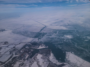 Flying over southeast michigan during the winter on a cloudy day with snow and ice on the ground. 