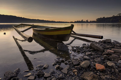 Boats moored on sea against sky during sunset