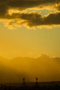 Silhouette landscape against orange sky