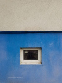 Low angle view of blue window on wall of building