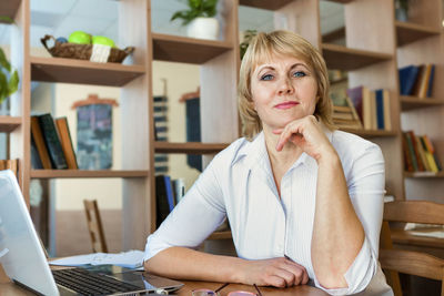 Portrait of woman sitting on table at home