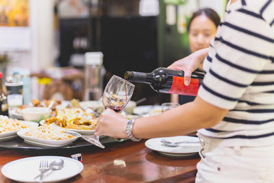 Midsection of woman hand pouring red wine.