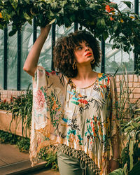 Woman looking away while standing against plants