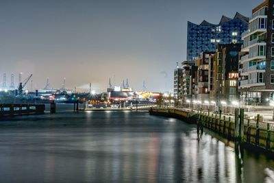 Boats moored at harbor against clear sky at night