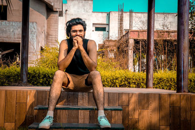 Portrait of young man sitting on wood