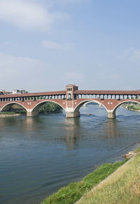 Arch bridge over river against sky
